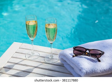 Two Glasses Of Sparkling Champagne Or Prosecco On A White Wooden Table Next To The Swimming Pool In Summer.
