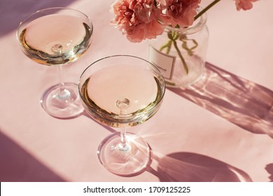 Two Glasses Of Sparkling Wine On The Pink Table In Natural Sunlight With Shadows.