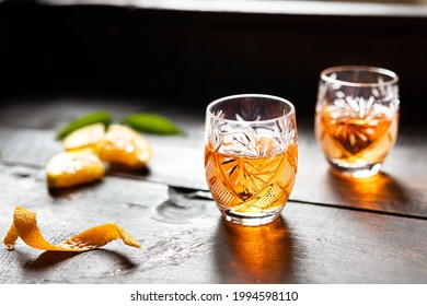 Two glasses with tangerine liqueur on an old wooden background