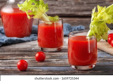 Two glasses of tomato juice on a wooden table, on a wood background, fresh drink