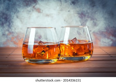 Two Glasses Of Whiskey With Ice. Still Life. Brandy, Bourbon On A Brown Wooden Table. Strong Alcohol Drink. Rum, Scotch. 