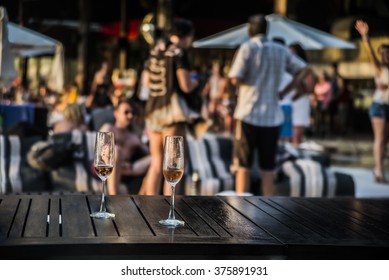 Two Glasses Of White Or Red Vine Against Group Of People. Hot Beach Party. Sexy People