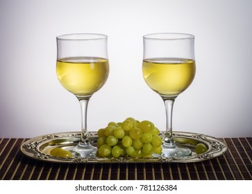 Two glasses of white wine and a bunch of green grapes on a metal dish / Photo taken in a personal photographer studio - Powered by Shutterstock