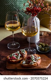 Two Glasses Of White Wine And Gorgonzola Bruschetta Figs In A Cozy Interior On A Wooden Table