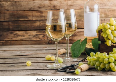 Two glasses of white wine and grape on vintage wooden table. Selective focus with copy space