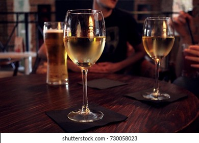 Two glasses of white wine and a mug of lager beer on a wooden table