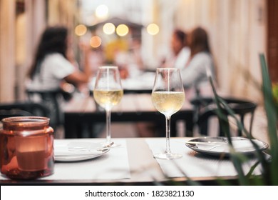 Two Glasses Of White Wine On A Table With Candles, All Set For A Romantic Dinner Date, Outdoor Cafe