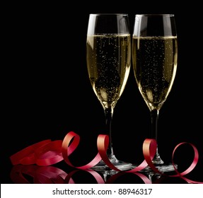 Two Glasses With White Wine Over Black Background With Red Ribbon