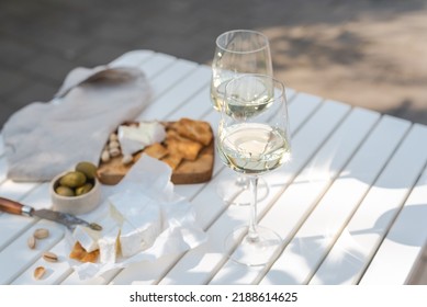 Two glasses of white wine and a wooden plate of cheese and nuts in the backyard. - Powered by Shutterstock