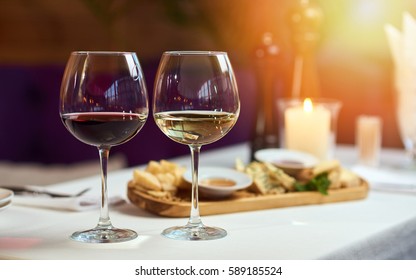 Two Glasses Of Wine White And Red Standing On A Table With Candle In The Sun Light 