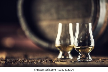 Two Glencairn Whisky Tasting Glasses On Vintage Wood And Dark Wooden Barrel In The Back.