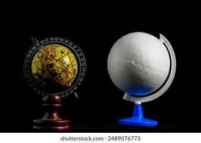 Two globes, one of which is a small model of the Earth. The other is a white ball