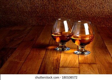 Two goblets of brandy on wooden old counter top 