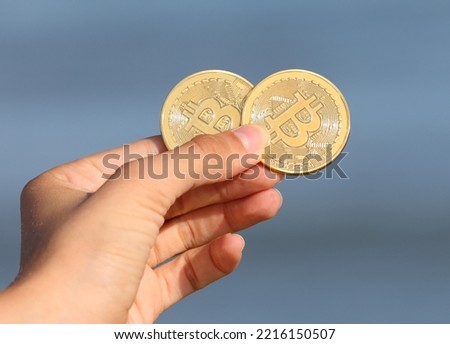 two golden coins symbolizing bitcoins in hand
