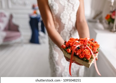 Two golden wedding rings laying on tray of orange roses. in the hands of women. accessories for the bride and groom. Preparation for the ceremony