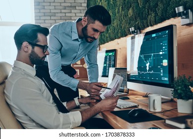 Two good looking young modern men in formalwear analyzing data while working in the office - Shutterstock ID 1703878333