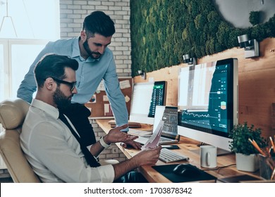 Two good looking young modern men in formalwear working using computers while sitting in the office - Shutterstock ID 1703878342