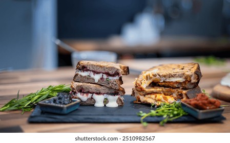 Two gourmet grilled cheese sandwiches sit temptingly on a slate board, one with a sweet and savory combination of melted cheese . - Powered by Shutterstock