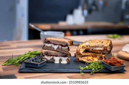 Two gourmet grilled cheese sandwiches sit temptingly on a slate board, one with a sweet and savory combination of melted cheese . - Powered by Shutterstock