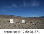 Two graves with headstones in the vast desert.