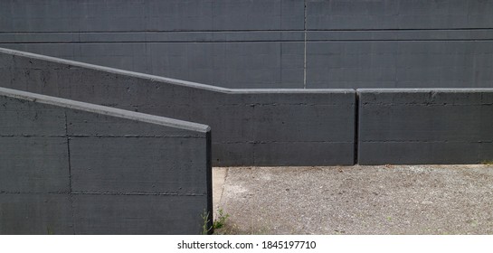 Two gray concrete parapets with a high wall behind them of the same color. A concrete footway among they. Urban background for copy space. - Shutterstock ID 1845197710