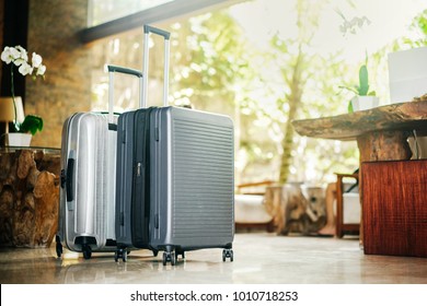 two gray large suitcases stand in the lobby of the hotel on the background of the waiting room and tropical greenery. The concept of vacation and travel.