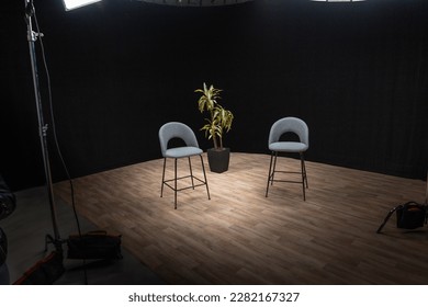 Two gray stools and plant in a TV studio setup. Lighting, atrezzo ready to shoot. Interview scene. 