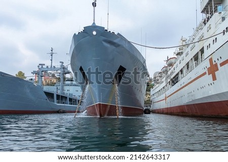 Two gray warships of the Russian Navy and a white hospital ship in port on the Black Sea