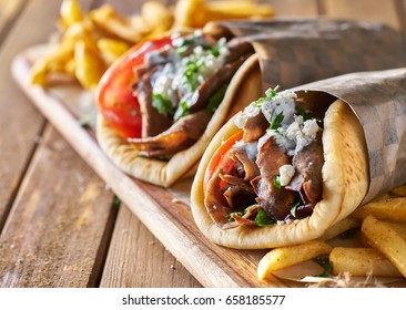 two greek gyros with shaved lamb and french fries
