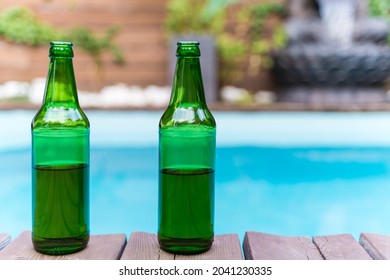 Two Green Bottles Of Beer Without A Logo Outside. Swimming Pool In The Tropics. Alcohol At A Patio Party. No People