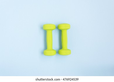 Two Green Dumbbells Over Blue Background, Top View. Sport Concept