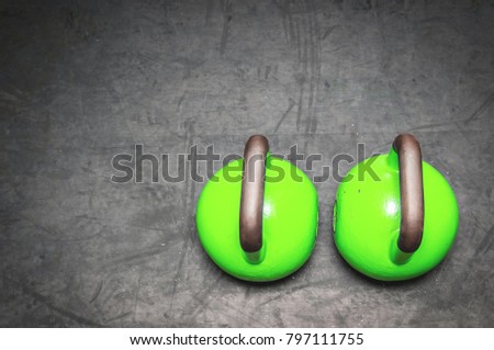 Two green kettlebells on the gym floor ready to use for fitness training sport concept view from above