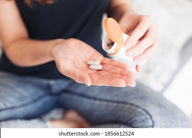 Two grey pills and an orange box in women's hand
