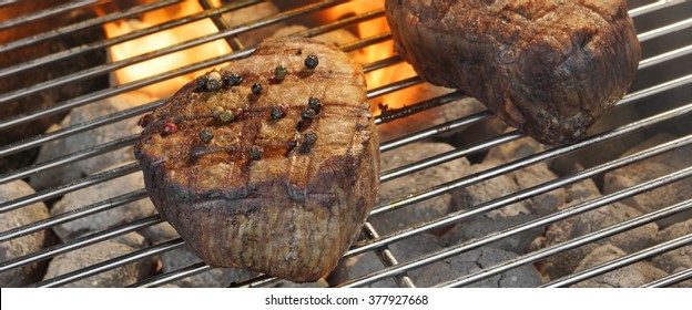 Two Grilled Beef Fillet Medallions On The Flaming Barbecue Grill, Outdoor Scene, Top View, Close Up. Backyard Party Or Picnic Concept.