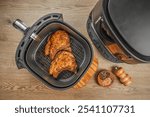 Two grilled steaks from air fryer oven on a wooden background, easy crispy food with little or no fat by circulating hot air inside the basket,