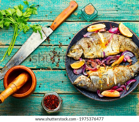Two grilled trouts with lemon and onion on plate
