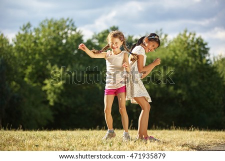 Two grils under the sunshine dancing in summer at the park