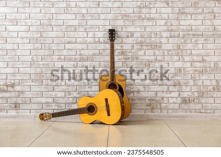 Two guitars near brick wall