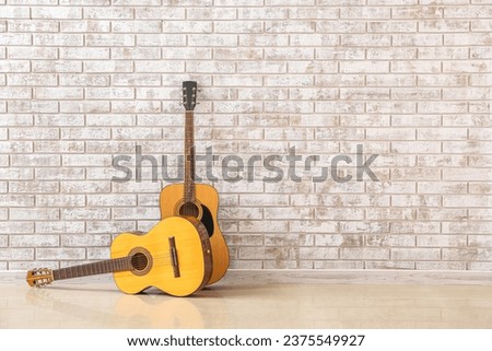 Two guitars near brick wall