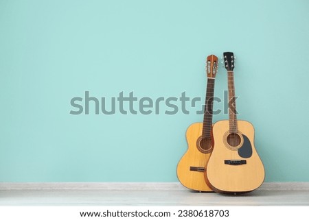 Two guitars near color wall