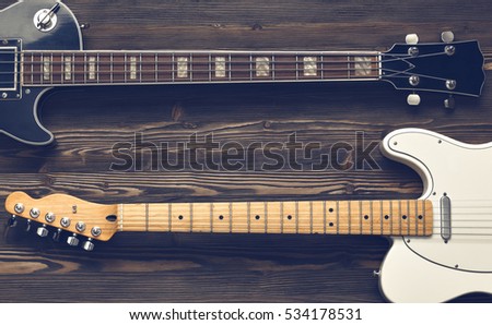 Two guitars on a dark wooden board.