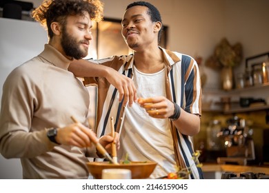 Two Guys Of Different Ethnicity Having Fun While Making Salad Together On Kitchen. Concept Of Gay Couples And Everyday Life At Home . Caucasian And Hispanic Man Cooking Healthy Food