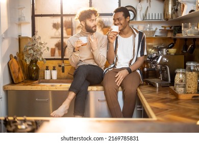 Two guys of different ethnicity having warm conversation while sitting with coffee on kitchen at home. Concept of close male friendship or relationship as gay. Caucasian and hispanic man together - Powered by Shutterstock