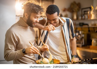 Two guys of different ethnicity having fun while making salad together on kitchen. Concept of gay couples and everyday life at home . Caucasian and hispanic man cooking healthy food - Shutterstock ID 2189203721