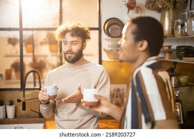 Two guys of different ethnicity having warm conversation while drinking coffee on kitchen at home. Concept of close male friendship or relationship as gay couple. Caucasian and hispanic man together - Powered by Shutterstock