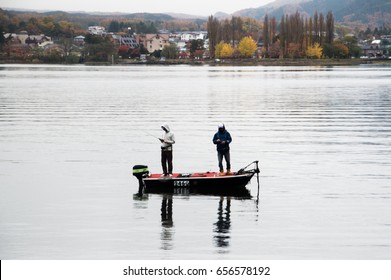Two Guys Fishing On The Boat In The Middle Of The Lake On The Morning 