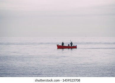 Two Guys Fishing On A Small Red Boat