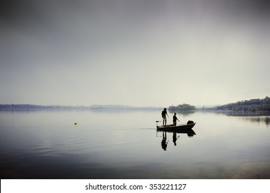 Two Guys Fishing On A Small Boat In The Lake Of Pusiano, Italy