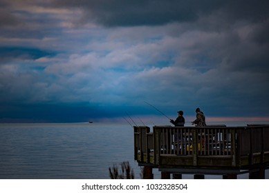 Two Guys Fishing From A Peer On A Lake