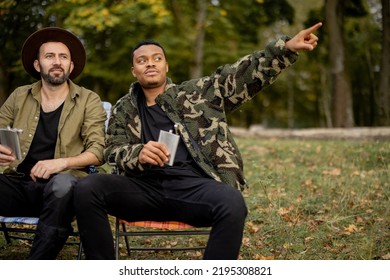 Two Guys Having Fun, Drinking Alcohol While Fishing Together On The Lake Coast. Caucasian And Latin Man Resting On Nature. Concept Of Male Friendship And Alcoholic Drinks